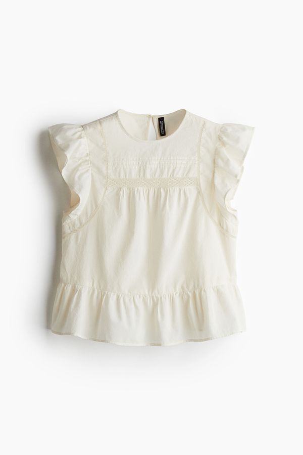 Blusa con inserciones de encaje y peplo